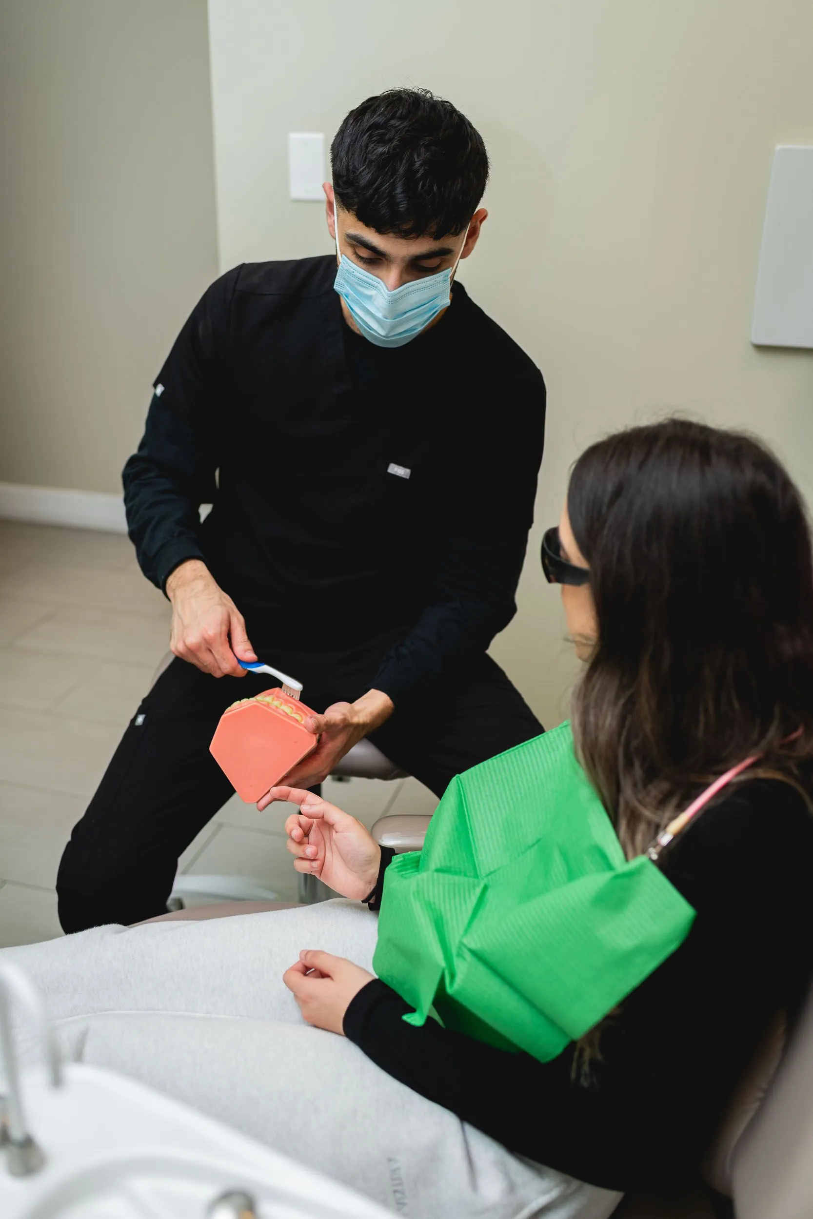 A dental hygienist showing a patient tooth brushing technique and how dental bonding can work.