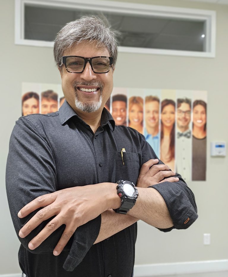 Dr. Sharib Manzoor standing in MI Dental office, smiling in a professional setting